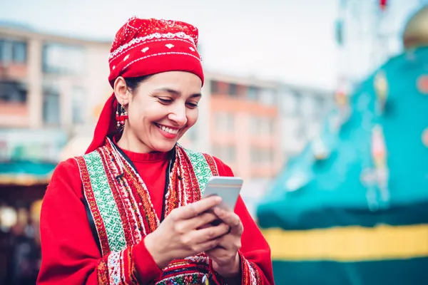 Uma jovem relaxando com o celular enquanto elementos dinâmicos de cassino flutuam ao seu redor, ilustrando a experiência móvel fluida oferecida pelo app BB22.