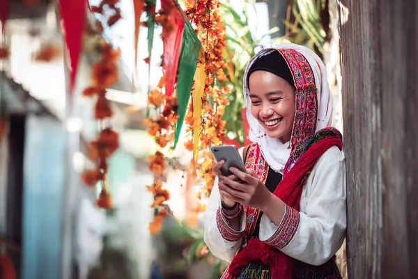 Um jogador usando seu smartphone durante um evento festivo local, representando o cassino totalmente compatível com dispositivos móveis do BB22.